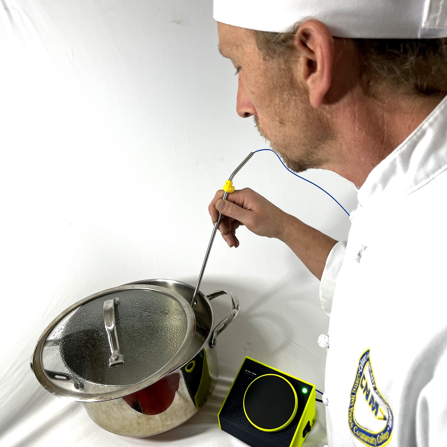 A cook's hand lowering the thermocouple probe into a covered pot