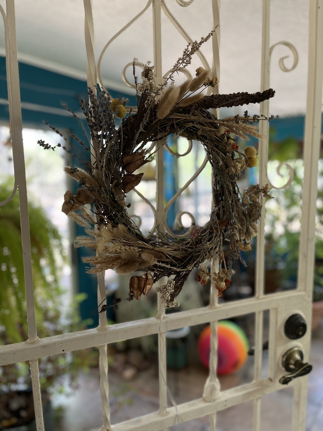 The wreath hung on a white wrought-iron gate in daylight