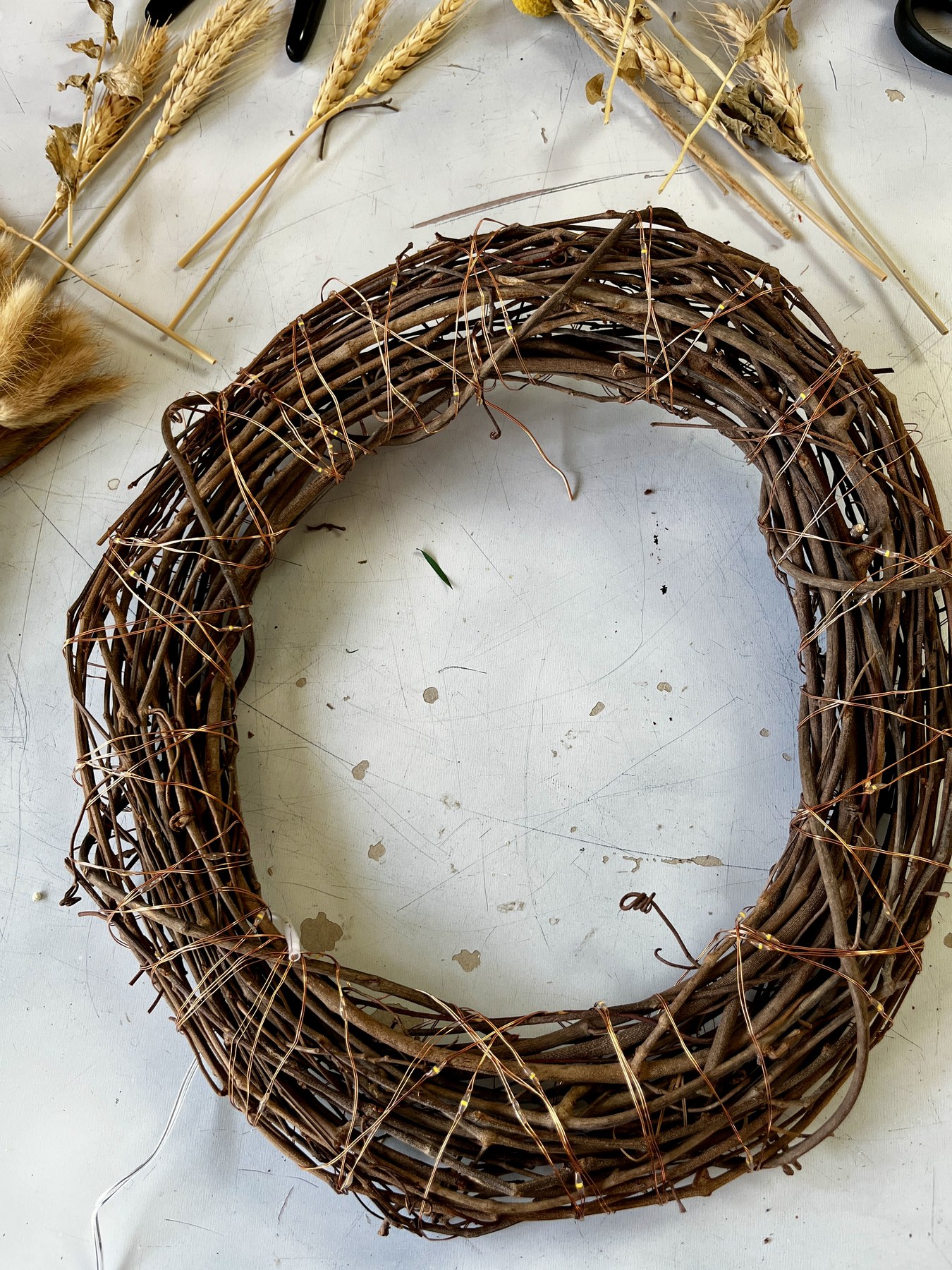 The bare twig wreath base before anything is added, materials laid out around it